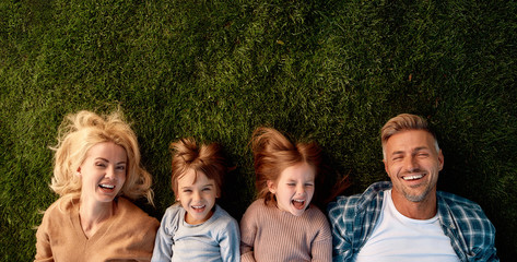Family vacation. Happy family of four lying on green grass