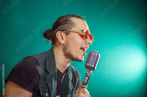 Latin man singer with retro microphone watching the cell phone on white background photo