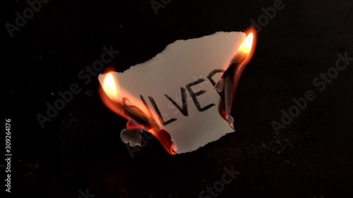 Silver word written on white paper burns. Fire with smoke and ashes on black background photo