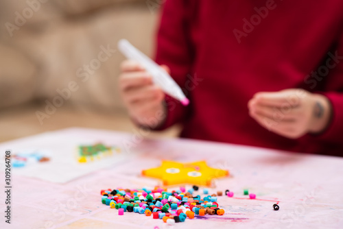 Colorful fusible beads or perler beads, on the children's table. Toy that develops the imagination of child. Soft blurred background with space for text.