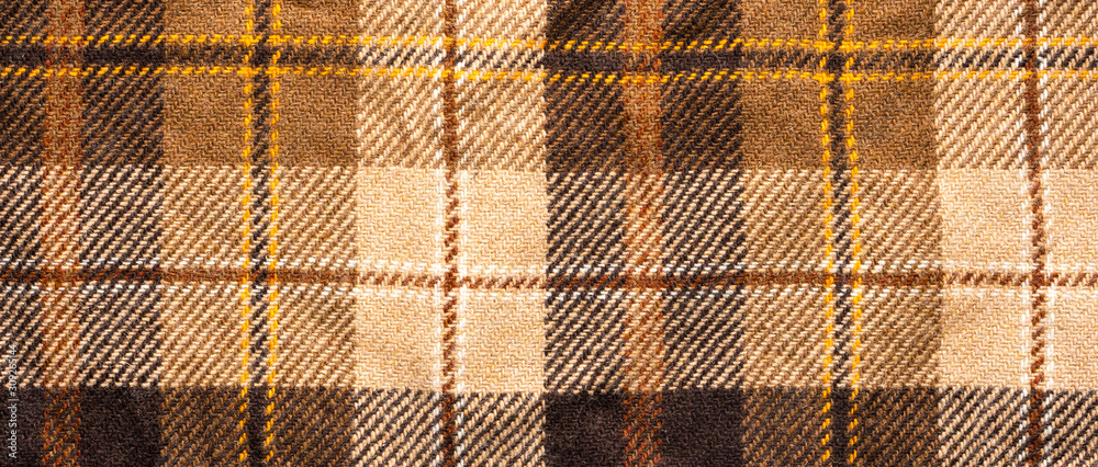 Brown checked fabric. Scottish wool. Fabric for coat plaid suit. Close-up. Background