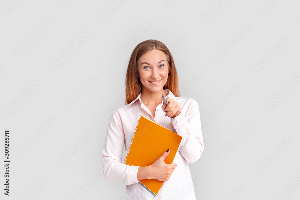 Freestyle. Young businesswoman standing isolated on white with notebook pointing at camera smiling cheerful Freestyle. Young businesswoman standing isolated on white with notebook pointing at camera smiling cheerful