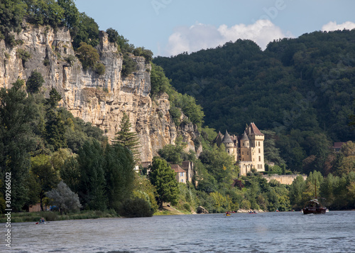  Canoeing and tourist boat, in French called gabare, on the river Dordogne at La Roque-Gageac and Chateau La Malartrie in the background. Aquitaine, France