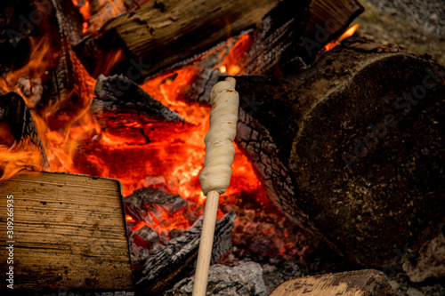 Preparing stick bread in the embers of a campfire