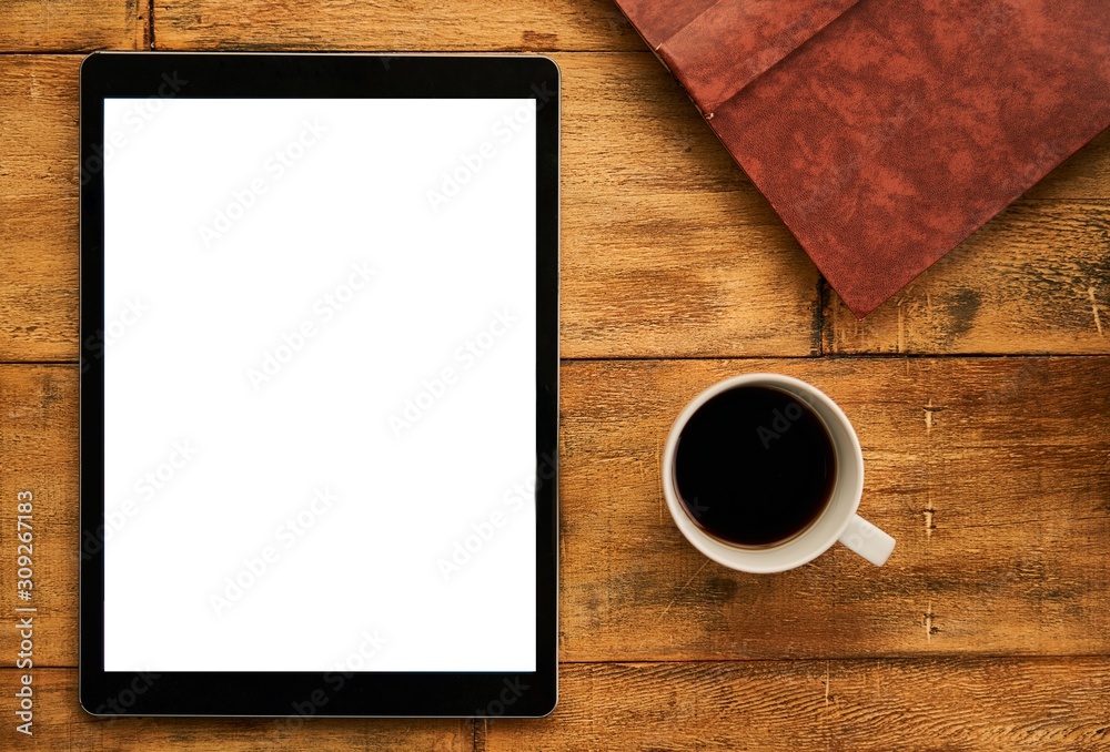 Blank tablet on wooden table with a cup of coffee and a book. Blank tablet on wooden table with a cup of coffee and a book.
