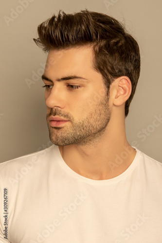 Muscle strong face beautiful stripped male model portrait in white t-shirt on grey isolated font background with shadow