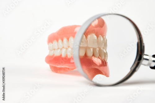 Diagnosis prosthetics treatment concept. Artificial teeth and magnifying glass
