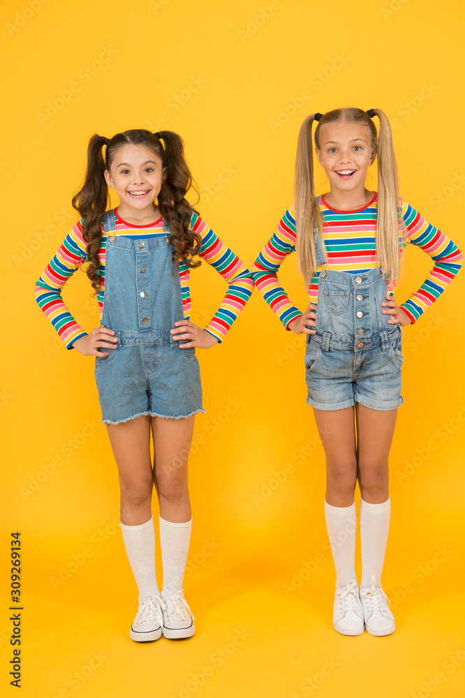 Vibrant colors. Modern fashion. Kids fashion. Girls long hair. Cute  children same outfits. Little girls wearing rainbow clothes. Matching  outfits. Trendy and fancy. Fashion shop. Must have accessory Stock Photo