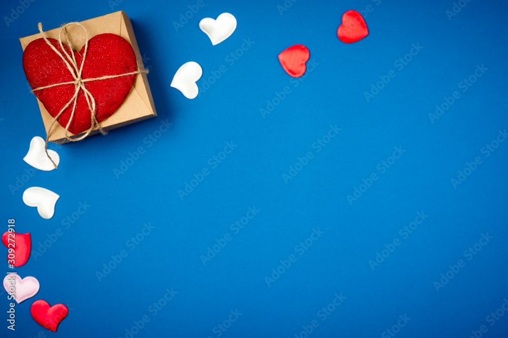 Red heart with a gift to Valentine's Day on a beautiful blue background. Heart pendant. Space for text. Red heart. Valentine Day. Red heart with a gift to Valentine's Day on a beautiful blue background. Heart pendant. Space for text. Red heart. Valentine Day.