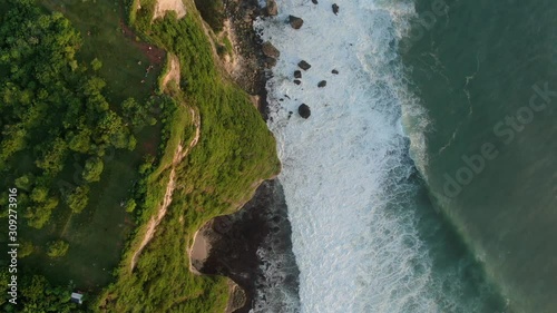 Landscape from Pura Uluwatu cliff. Waves break on rocky shore. Seascape, rocks, ocean.