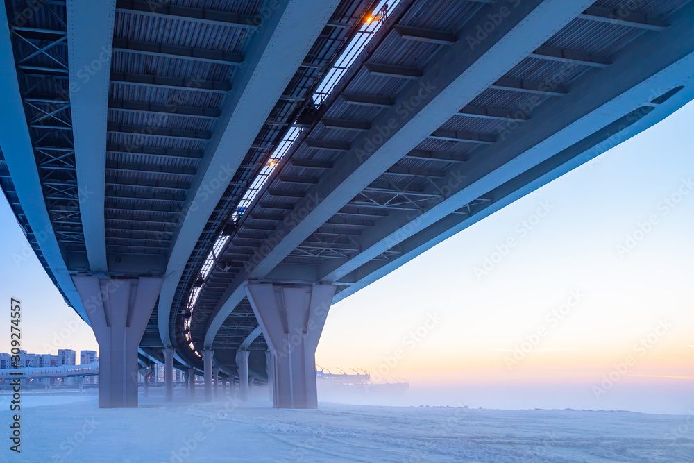 Bridges. Winter panorama from under the bridge. The construction of bridges. Winter city landscape. Concept - bridge maintenance. Bridge supports. City architecture. Frozen river Frozen channel. Snow Bridges. Winter panorama from under the bridge. The construction of bridges. Winter city landscape. Concept - bridge maintenance. Bridge supports. City architecture. Frozen river Frozen channel. Snow