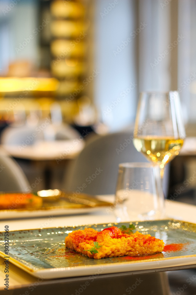 detail of saffron risotto dish with chilli and glass of white wine in a luxury Italian restaurant detail of saffron risotto dish with chilli and glass of white wine in a luxury Italian restaurant