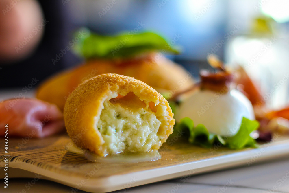 detail of open croquette with mozzarella inside on a tray of typical Napolitan snacks such as buffalo mozzarella, savory puff pastry, black pig salami from Caserta, ham and cheese, montanara detail of open croquette with mozzarella inside on a tray of typical Napolitan snacks such as buffalo mozzarella, savory puff pastry, black pig salami from Caserta, ham and cheese, montanara