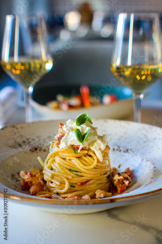 haute cuisine dish with spaghetti with lobster, buffalo stracciatella and a fine white wine. In a luxurious Italian restaurant