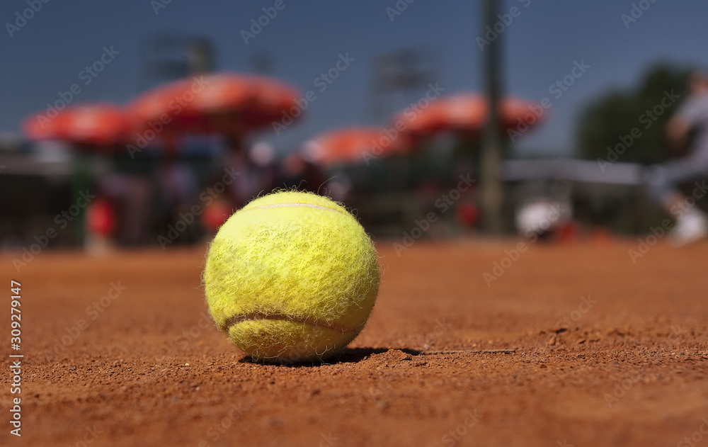 Yellow tennis ball on the clay court, close up.