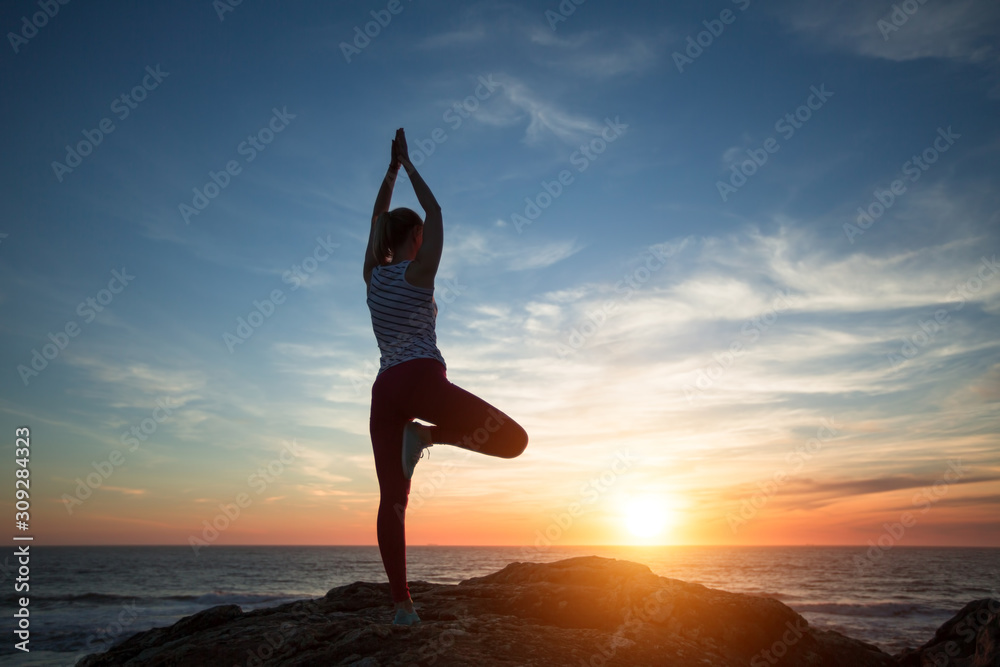 Yoga woman silhouette meditation on the sea beach at amazing sunset.