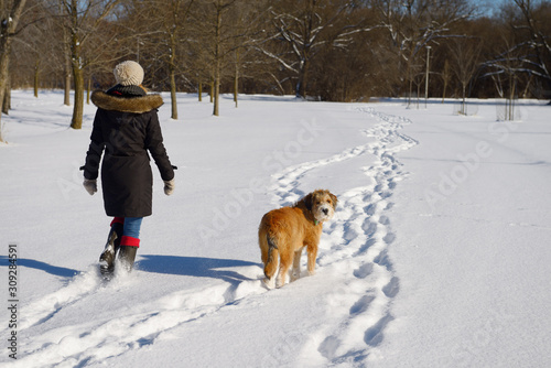Photography Young woman walking her dog in a Park with fresh snow