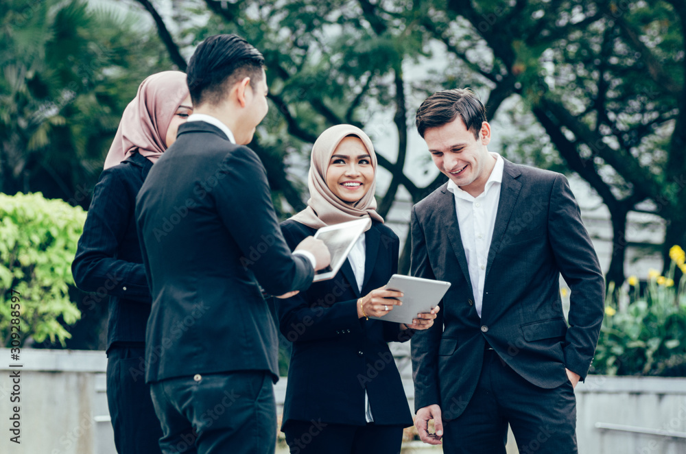 Group of young executive people in formalwear holding tablet and discussing something.happy face expression Group of young executive people in formalwear holding tablet and discussing something.happy face expression