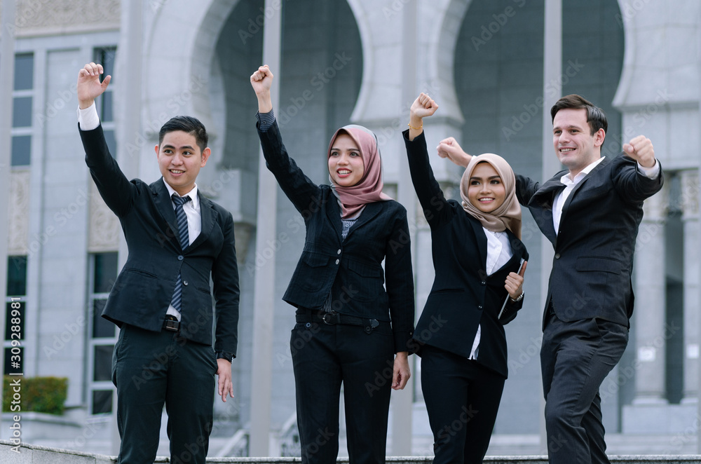 Group of young executive people in formalwear, arms raised to celebrate their success Group of young executive people in formalwear, arms raised to celebrate their success