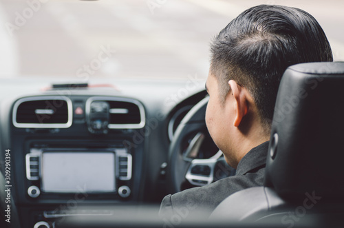 rear view young businessman sitting in his car and drive to work place