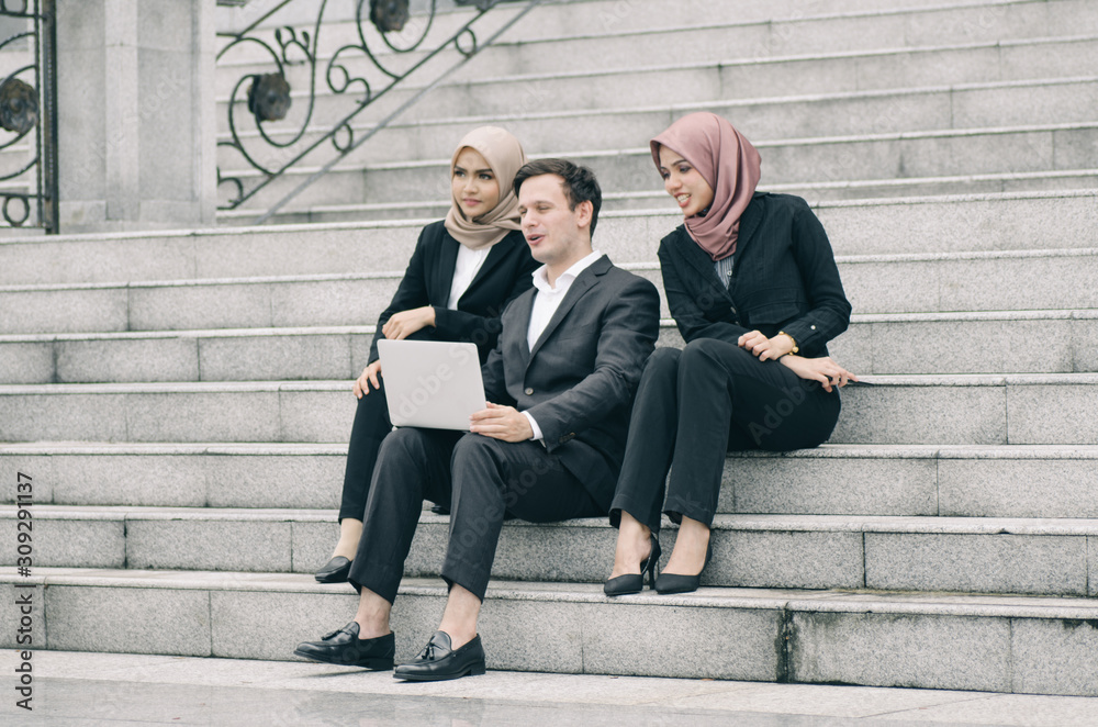 group young man and woman with hijab sitting and relax on stairs infront modern office