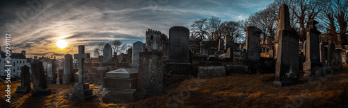 EDINBURGH, SCOTLAND DECEMBER 14, 2018: old, desolated and grungy tombstones, memorials and headstones in the graveyard with the sun rising at New Calton Burial Ground photo