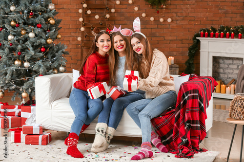 Beautiful young women with gifts celebrating Christmas at home © Pixel-Shot