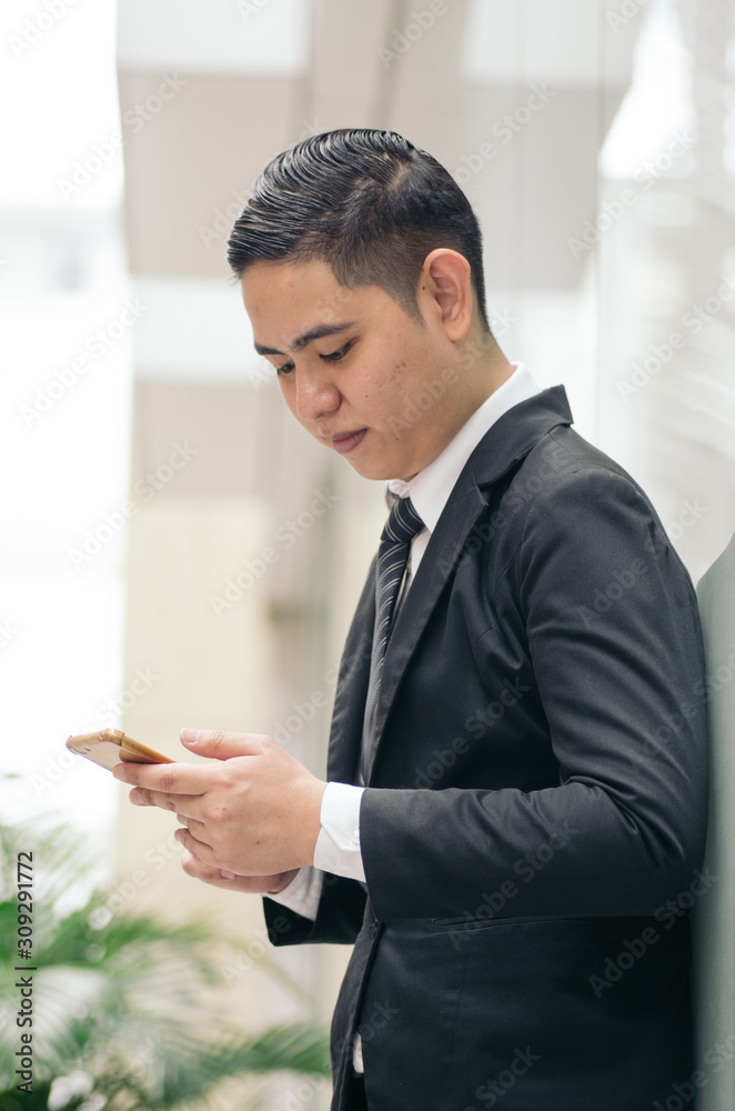 Portrait of young businessman Texting to Someone on his Mobile Phone with Happy Facial Expression. Portrait of young businessman Texting to Someone on his Mobile Phone with Happy Facial Expression.