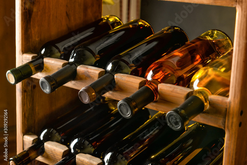 Wooden holder with bottles of wine in cellar photo