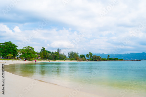 Beautiful clean Caribbean island beach on the coast of Montego Bay, Jamaica. Local people/ tourists having a relaxing weekend morning in this scenic setting. White sand and clear turquoise waters.