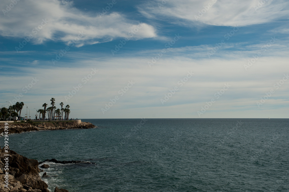 beautiful photo of beaches malaga city background, rocks and trees, palm trees and beautiful clouds in blue sky.