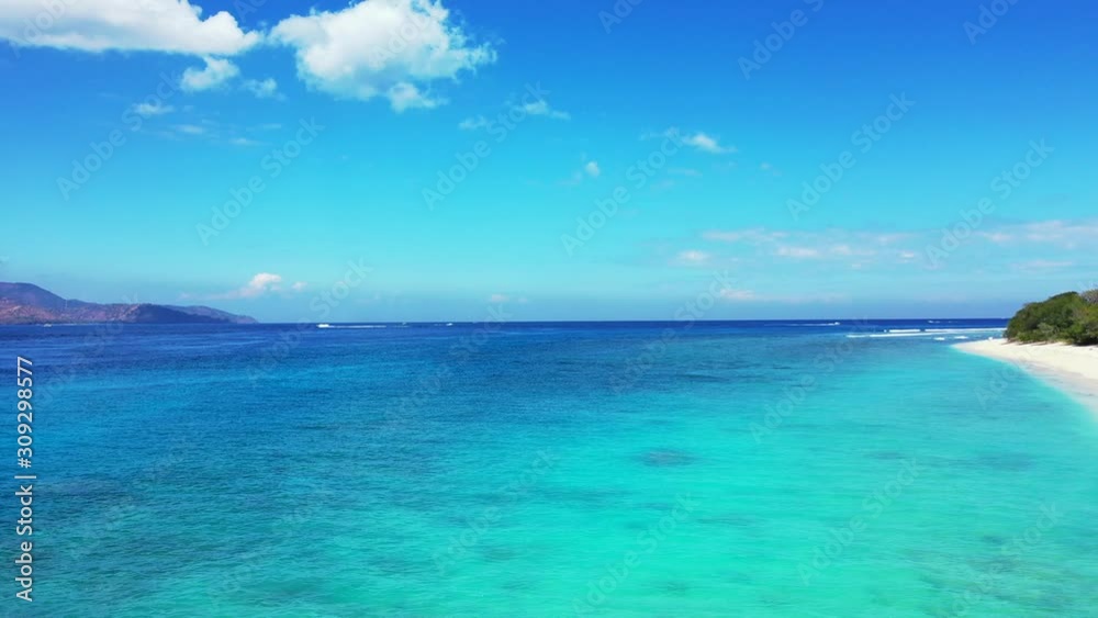 Glowing seascape with shiny turquoise lagoon around white sand of exotic beach under bright blue sky with static white clouds in Bali Glowing seascape with shiny turquoise lagoon around white sand of exotic beach under bright blue sky with static white clouds in Bali