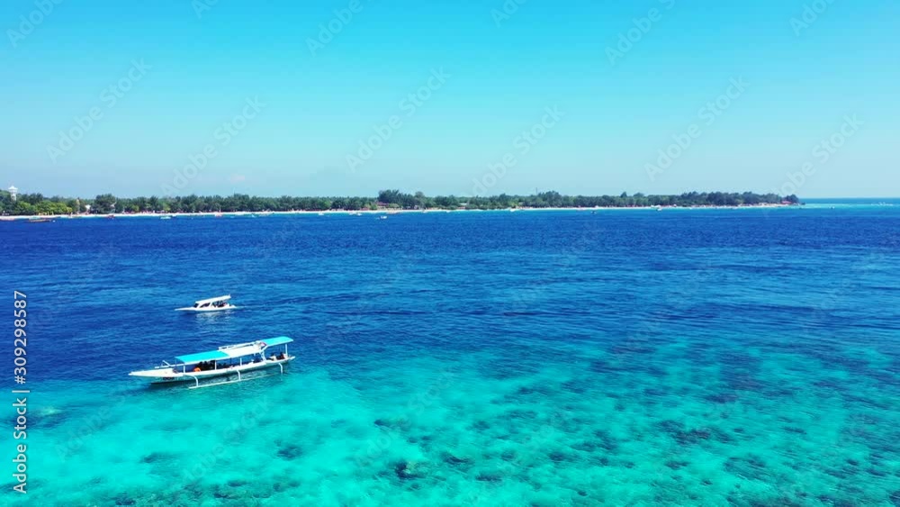 Touring boats floating on beautiful blue azure sea with rocky bottom seen through clear water around shore of tropical islands in Bali Touring boats floating on beautiful blue azure sea with rocky bottom seen through clear water around shore of tropical islands in Bali