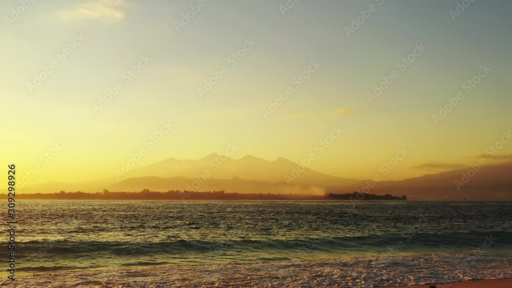 foamy waves splashing on the sandy beach. tropical island in the background. golden hour and romantic sunset foamy waves splashing on the sandy beach. tropical island in the background. golden hour and romantic sunset