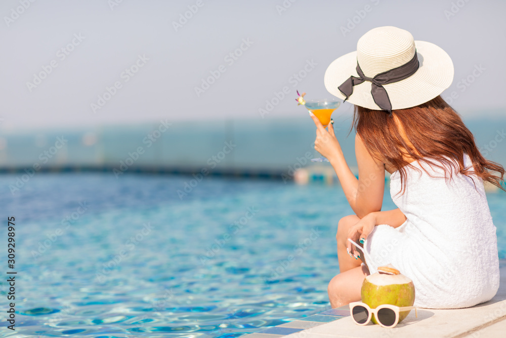 Portrait of a beautiful woman relaxing with orange juice at the swimming pool outdoors