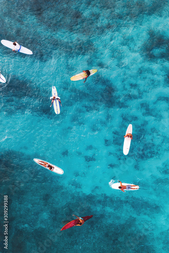 Aerial pic of surfers seating on surfboards and waiting for wave in the middle of ocean with perfect weather and clean water at sunset time in Hawaii paradise, shot on drone from above photo