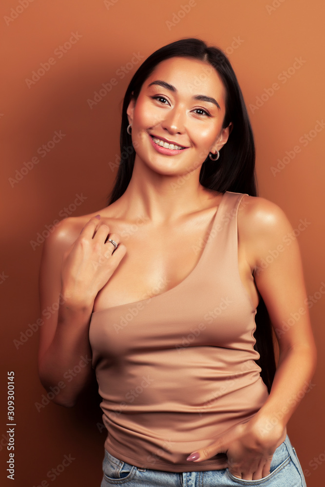 Obraz premium young pretty asian woman cheerful smiling posing on warm brown background, lifestyle people concept