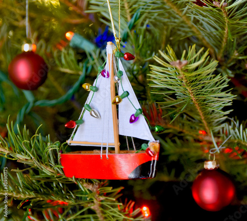 Red sailboat ornament hanging on a Christmas tree.  Closeup. 
