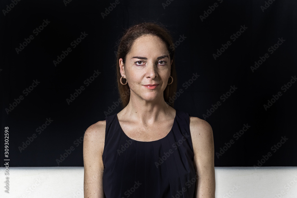 Portrait of a mature woman 45 - 50 years, looking camera with soft smile,  confident, fit body, over black background. foto de Stock | Adobe Stock