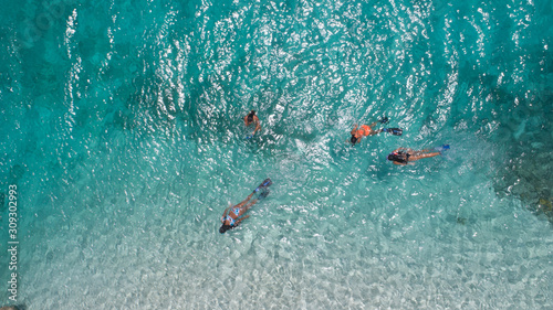 Young girls snorkeling in blue clear waters above coral reef on red sea in los roques venezuela . Travel and lifestyle concept. Top view. Three snorkelers swim in turquoise water