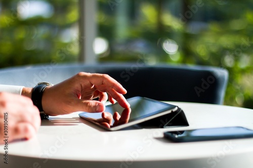 Close up of man using digital tablet at sunny interior, communication concept