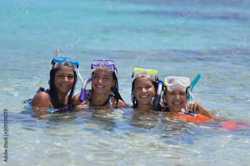 four Young multiracial girls snorkeling in blue clear waters at caribbean beach