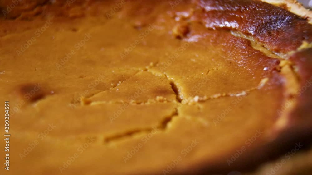 closeup macro shot of traditional homemade delicious natural pumpkin pie being cut and lifted from the pan. the tasty moist brown treat has a soft interior and great smell perfect for the holidays. closeup macro shot of traditional homemade delicious natural pumpkin pie being cut and lifted from the pan. the tasty moist brown treat has a soft interior and great smell perfect for the holidays.