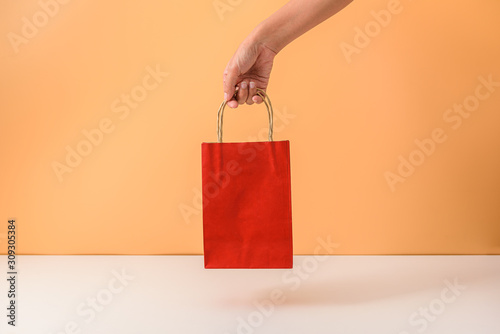 Female hand holding red papaer shopping bags
