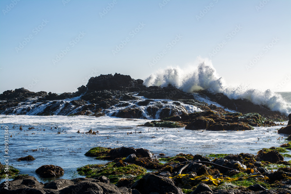 Crashing waves over jagged rocky ocean coastline  .