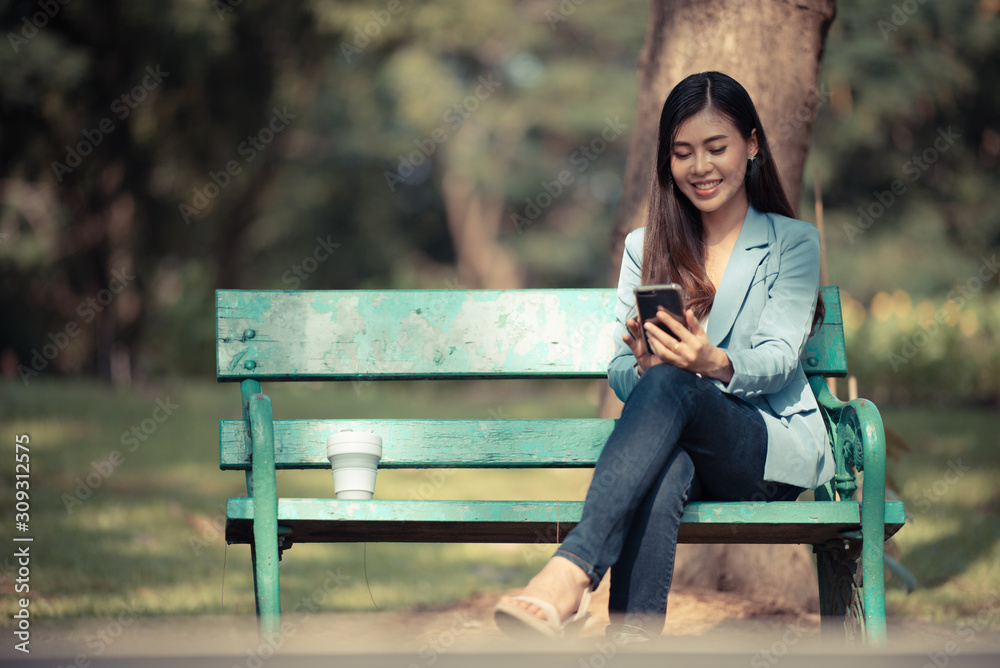 Asian business women are using smartphones to contact customers in the garden. Asian business women are using smartphones to contact customers in the garden.