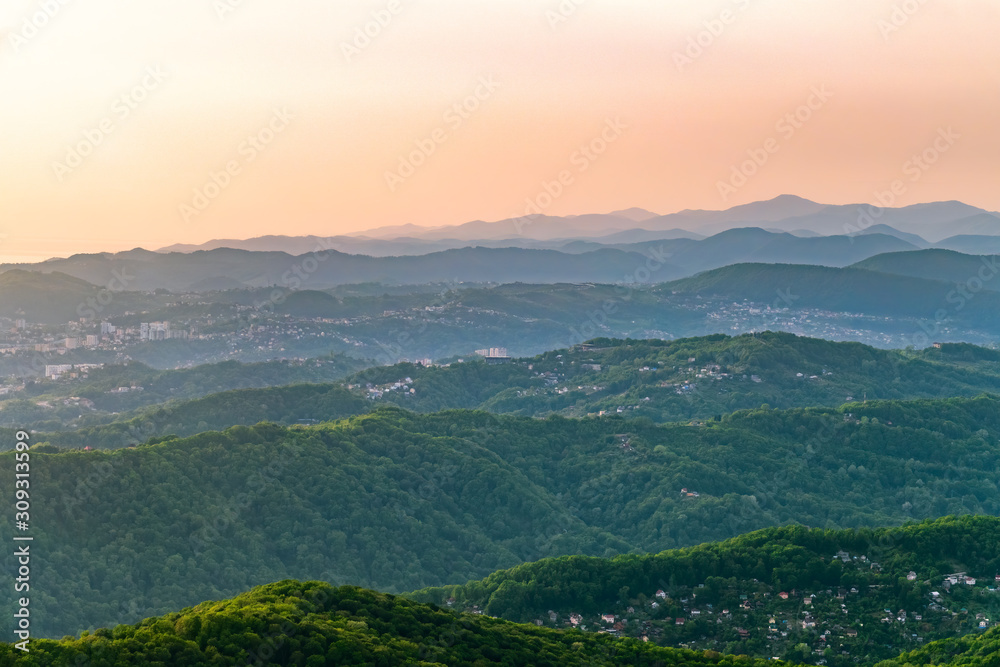 Layers of mountains and the Green valley with the city Sochi in the sunshine. View from Mount Akhun, Sochi, Russia.