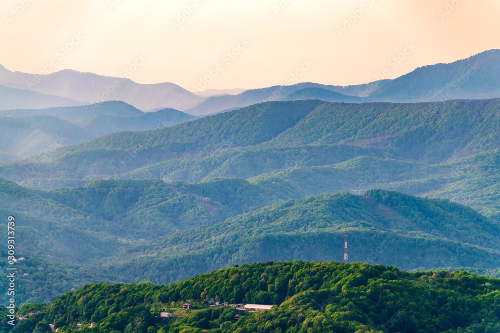 Obraz premium Layers of mountains in the haze during sunset. Beautiful sunset in the mountains. Beautiful sunset in a hilly valley with villages and fog in the lowlands.