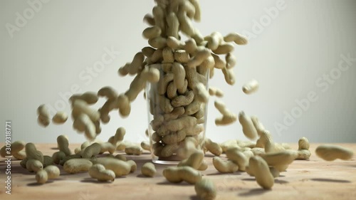 Peanuts Falling into a Cup on Wooden Floor. Nuts Overfill Glass Mug