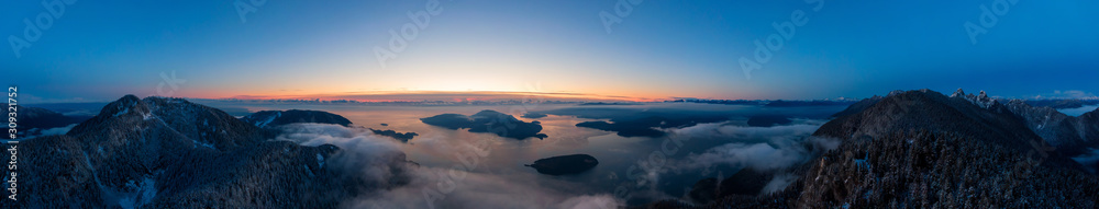 Fototapeta premium Panoramiczny widok z lotu ptaka na kanadyjski krajobraz górski na wybrzeżu Pacyfiku podczas kolorowy zachód słońca. Zrobiono w Howe Sound niedaleko Vancouver, Kolumbia Brytyjska, Kanada.